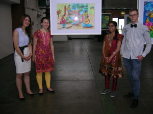 Die Organisatoren der Ausstellung (v.l.n.r.): Andrea, Jana, Thanaseela und Bastian. Das Bild im Hintergrund zeigt eine Szene aus dem Alltagsleben in Sri Lanka.
