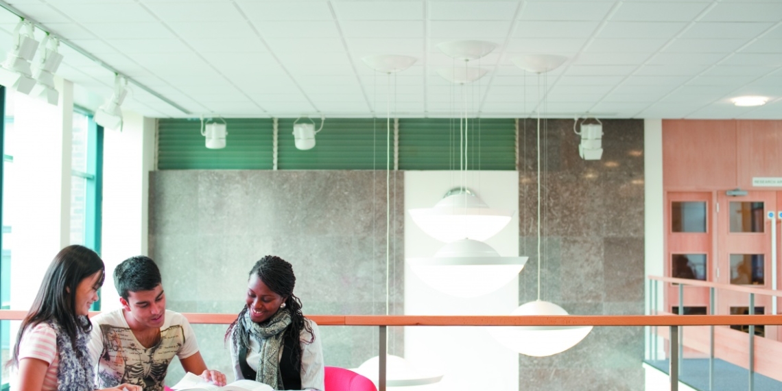 Drei internationale Studierende schauen sich gemeinsam ein Buch an