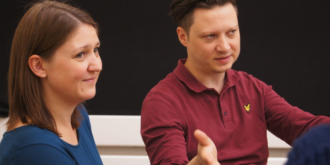 Frau und Mann im Gespräch mit Zuhörenden