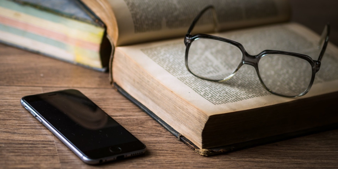 Ein Smartphone liegt neben einem Buch