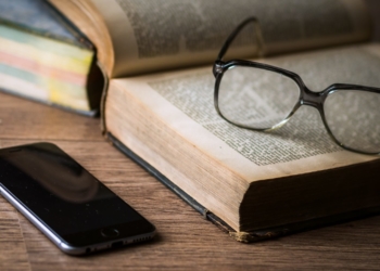 Ein Smartphone liegt neben einem Buch