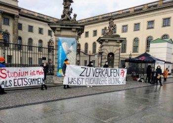 Berliner Studierende stehen mit Protestplakaten vor einem Universitätsgebäude. Auf einem großen Banner steht "Zu Verkaufen".