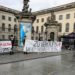 Berliner Studierende stehen mit Protestplakaten vor einem Universitätsgebäude. Auf einem großen Banner steht "Zu Verkaufen".